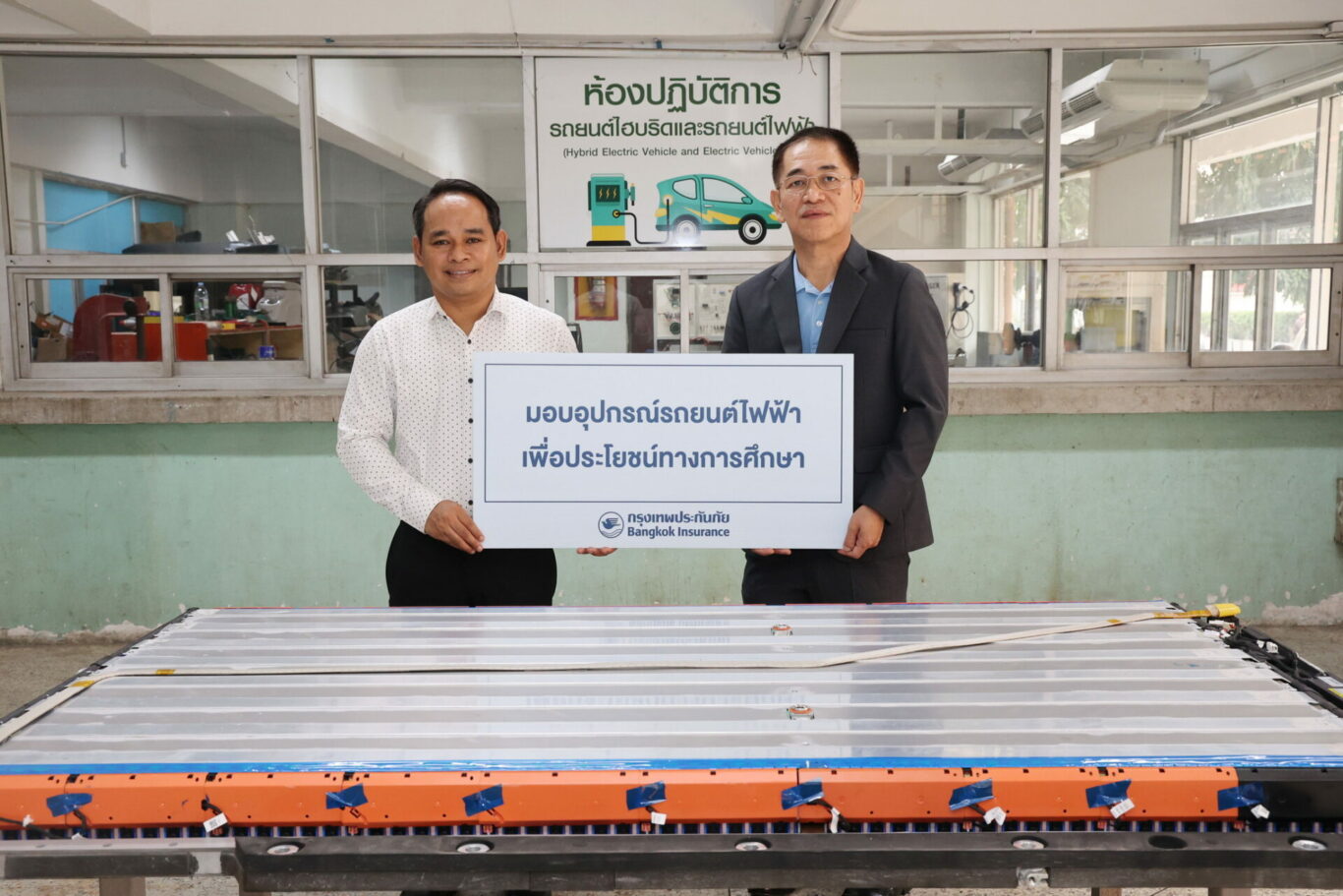 Men holding a sign in front of a conveyor belt

Description automatically generated