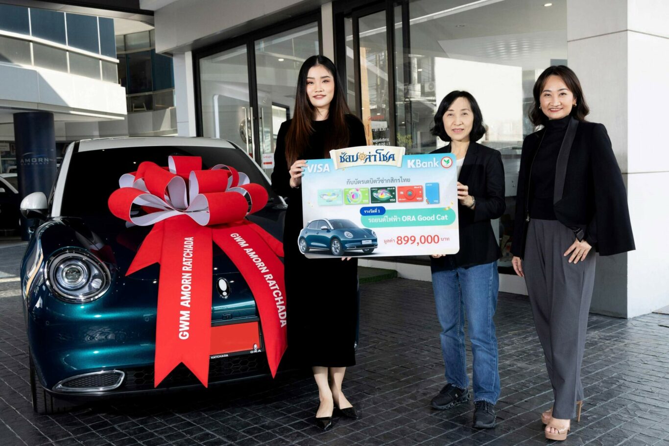 A group of women holding a sign and a car with a bow

Description automatically generated